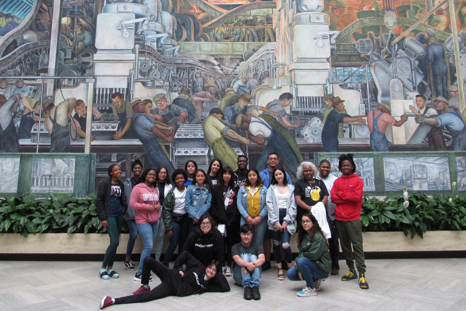 A group of students standing in front of a mural